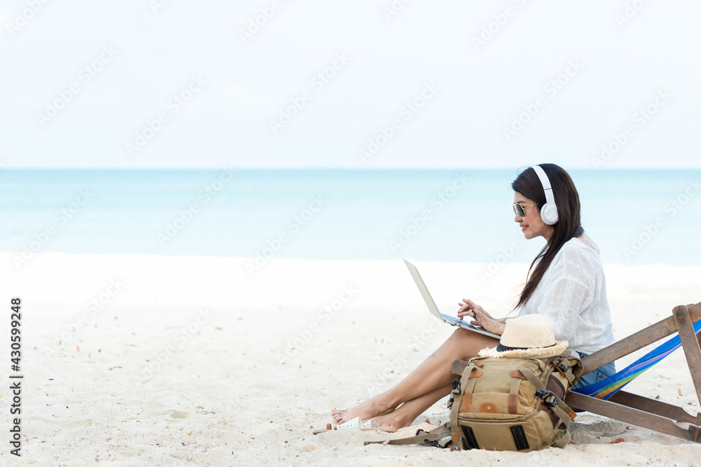 Lifestyle freelance woman using laptop working and relax on the beach.  Asian people success and together your work pastime and meeting conference on internet in holiday