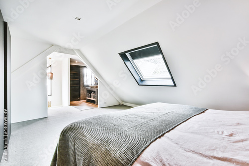 Interior of contemporary bedroom with white walls and open bathroom in attic of house photo