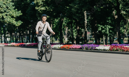 Cheerful young employee with helmet on utility bicycle rides to modern workplace