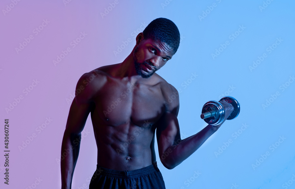 Portrait of millennial black bodybuilder exercising with dumbbells in neon light, panorama