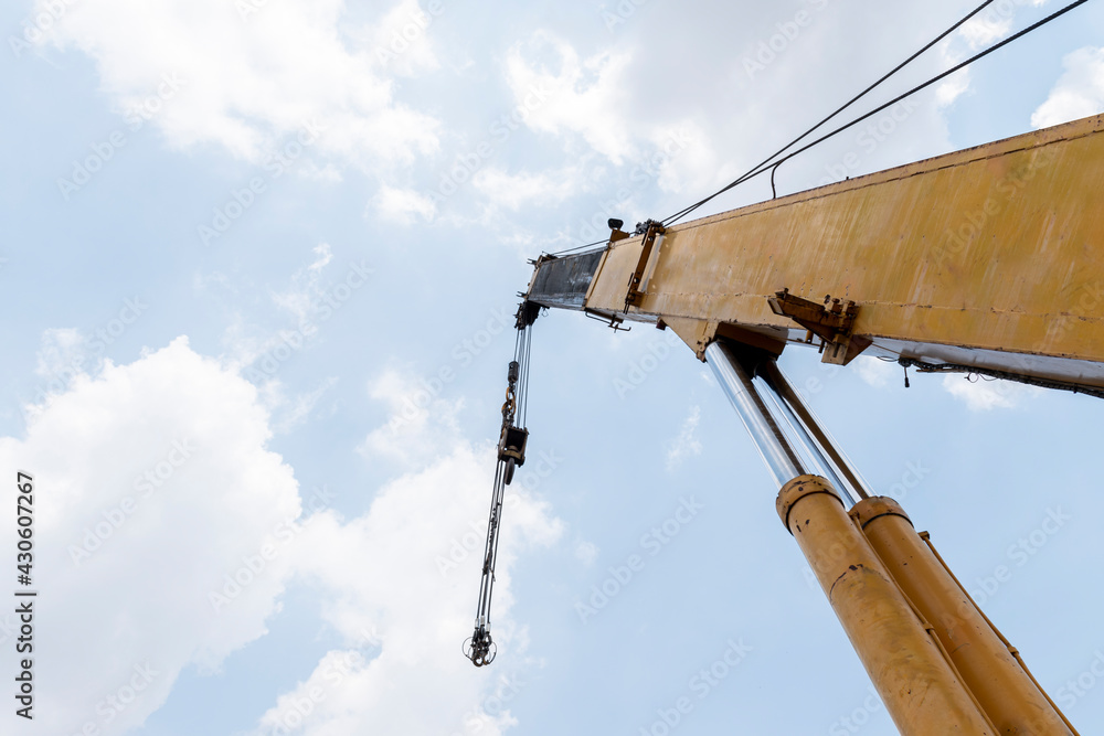Yellow crane boom with hooks and blue sky background Yellow crane boom with hooks and blue sky background