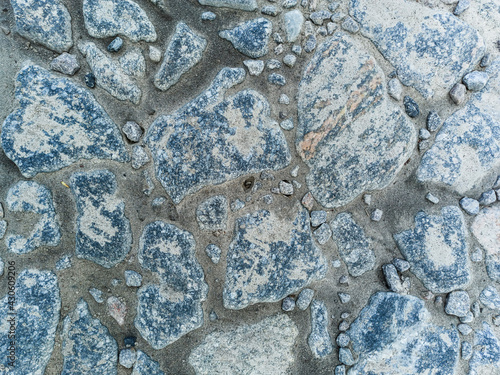 Piece of road paved with old cobblestones, abstract background, top view.
