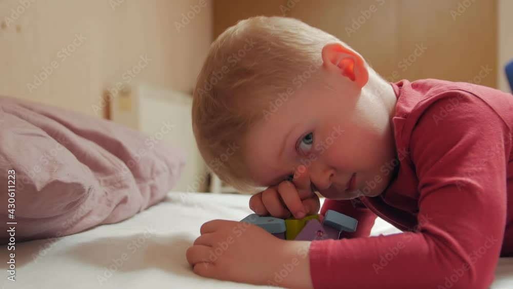 Boy rubs eyes with toy on bed closeup Boy rubs eyes with toy on bed closeup