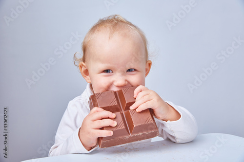 Child eats a large piece of chocolate. The concept of a junk food and healthy diet. Vegan chocolate.