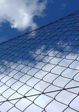 Metallic fence against vivid blue sky. Concepts of boundary, crisis, distance 