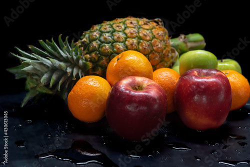 Mix fruit green apple pineapple orange red apple in splash water on black background.