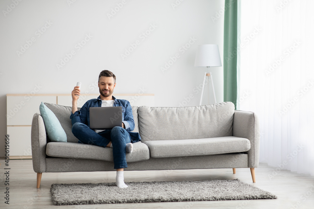 Relaxed man with laptop sitting on couch at home Relaxed man with laptop sitting on couch at home