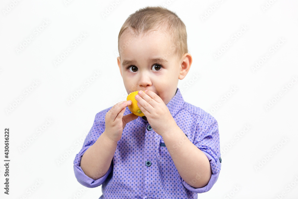 Caucasian boy 3 years old eating lemon on white background. Caucasian boy 3 years old eating lemon on white background.
