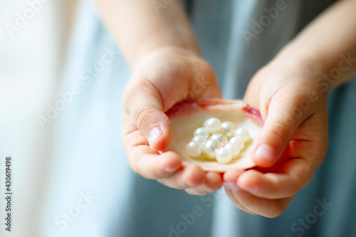 Children's hands hold oyster shell with pearls	