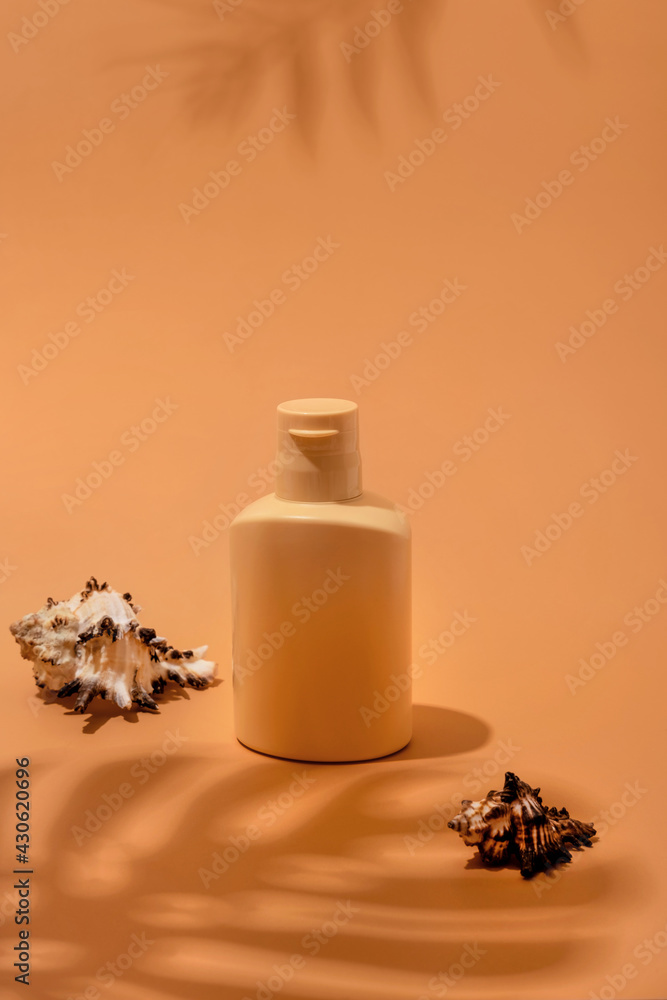 Bottle of sunscreen lotion on a beige background with shadows from tropical leaves. Skin care and protection concept. Golden tan. Bottle of sunscreen lotion on a beige background with shadows from tropical leaves. Skin care and protection concept. Golden tan.