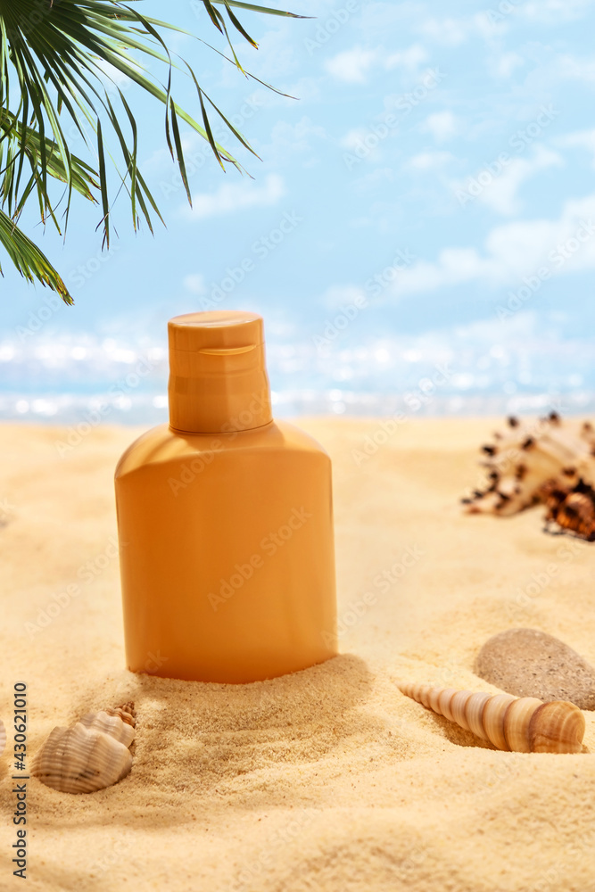 Bottle of sunscreen lotion on the sandy beach. Skin care and protection concept. Golden tan.