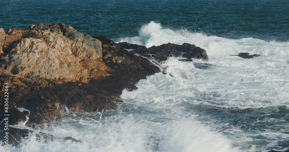 Ocean waves splash against rock on island