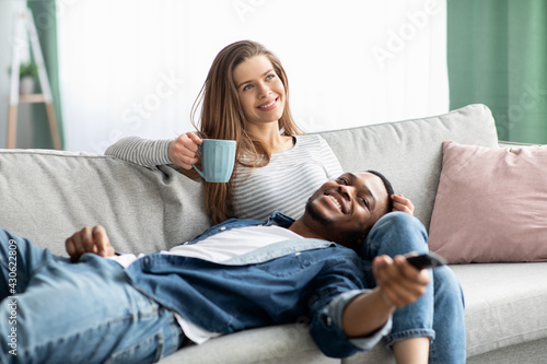 Home Pastime. Happy Interracial Couple Relaxing On Couch In Living Room Together
