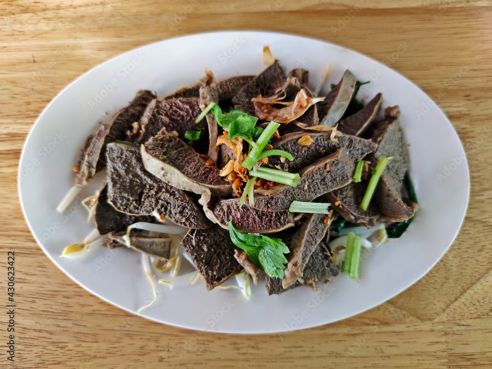 Delicious scalded beef spleen served in white plate on wooden table. Delicious scalded beef spleen served in white plate on wooden table.