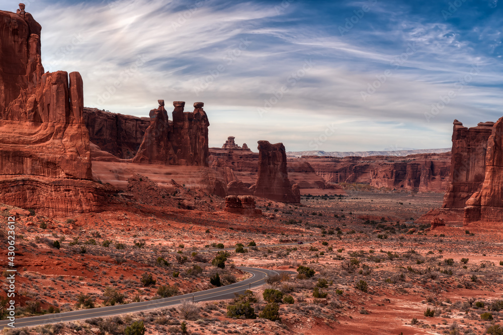 American landscape view of a Scenic road in the red rock canyons. Colorful Sky Artistic Render. Taken in Arches National Park, located near Moab, Utah, United States. Nature Background