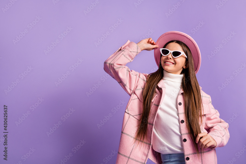 Portrait of charming dreamy cheerful girl wearing checked coat touching hat copy space isolated over bright violet purple color background Portrait of charming dreamy cheerful girl wearing checked coat touching hat copy space isolated over bright violet purple color background