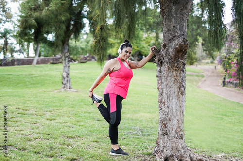 Active curvy woman doing stretching outdoor - Plus size girl, sport and healthy lifestyle concept