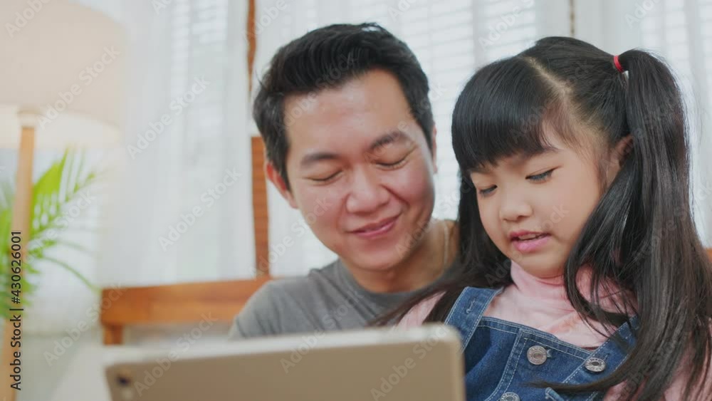 Asian father teaching daughter learn online at home by using tablet. Asian father teaching daughter learn online at home by using tablet.