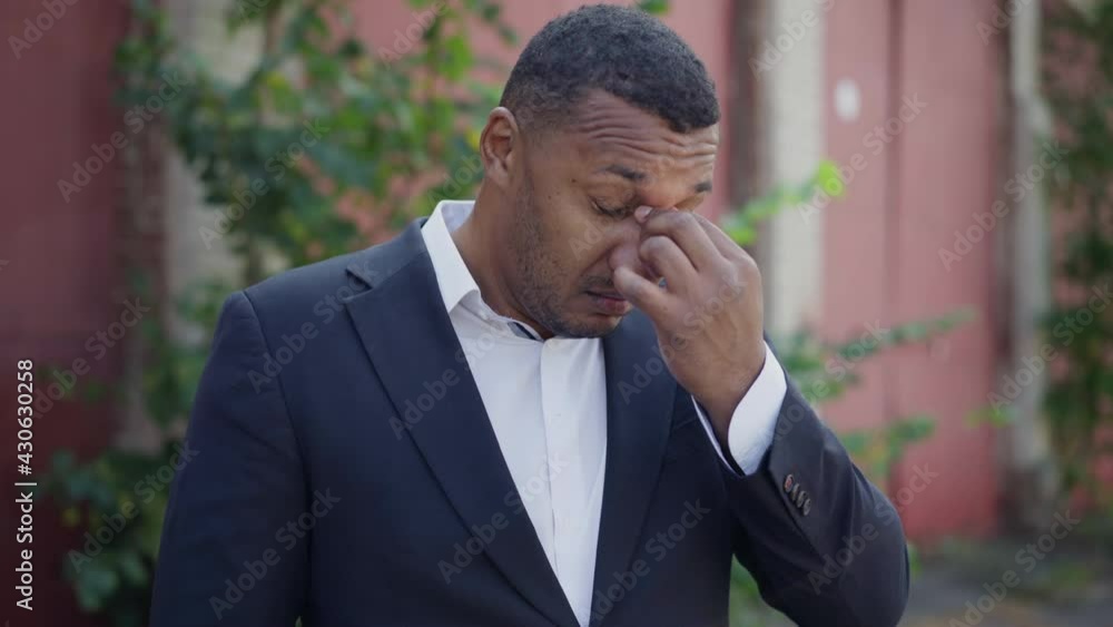 Tired young African American man rubbing eyes and putting on sunglasses standing outdoors. portrait of overworked exhausted businessman in suit. Tiredness and lifestyle Tired young African American man rubbing eyes and putting on sunglasses standing outdoors. portrait of overworked exhausted businessman in suit. Tiredness and lifestyle