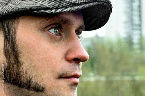Fotografia A green-eyed man with sideburns in a cap looks into the distance