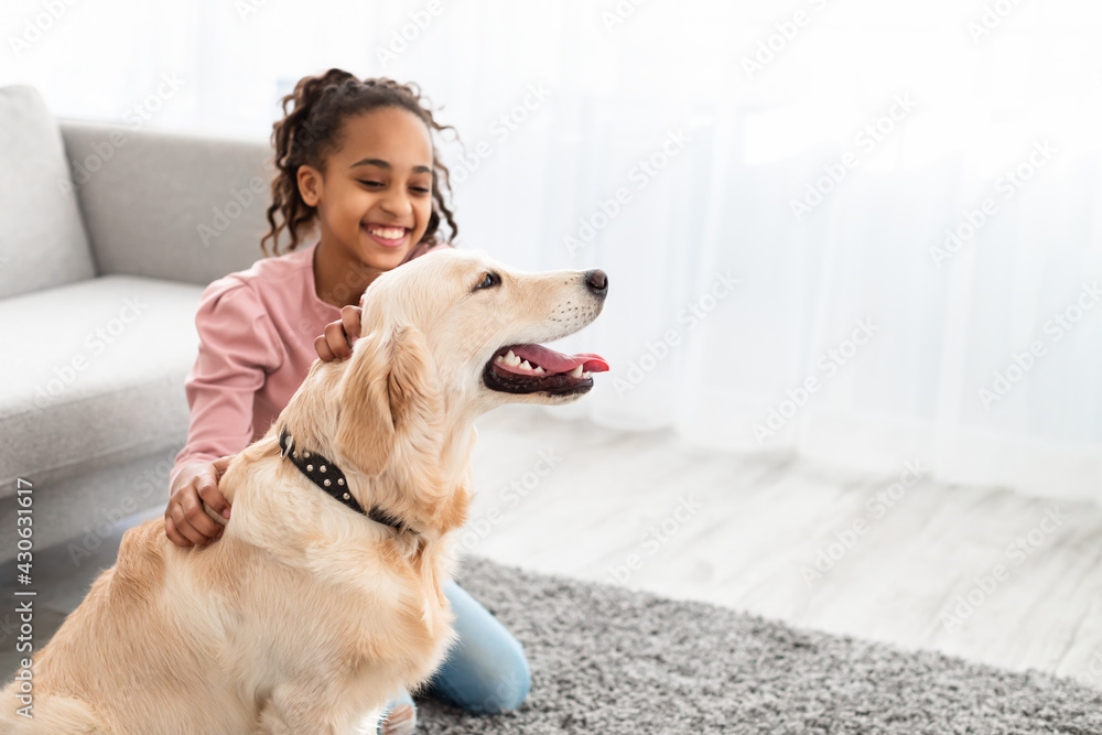 Young afro girl having fun with dog at home