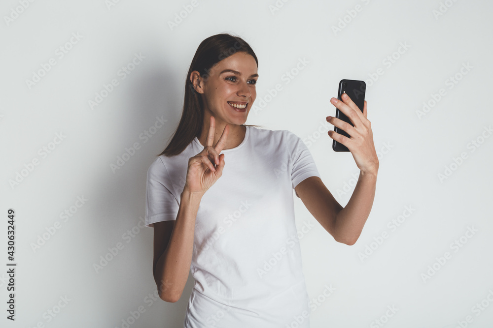 Front view of emotional woman blank white t-shirt with smartphone Front view of emotional woman blank white t-shirt with smartphone