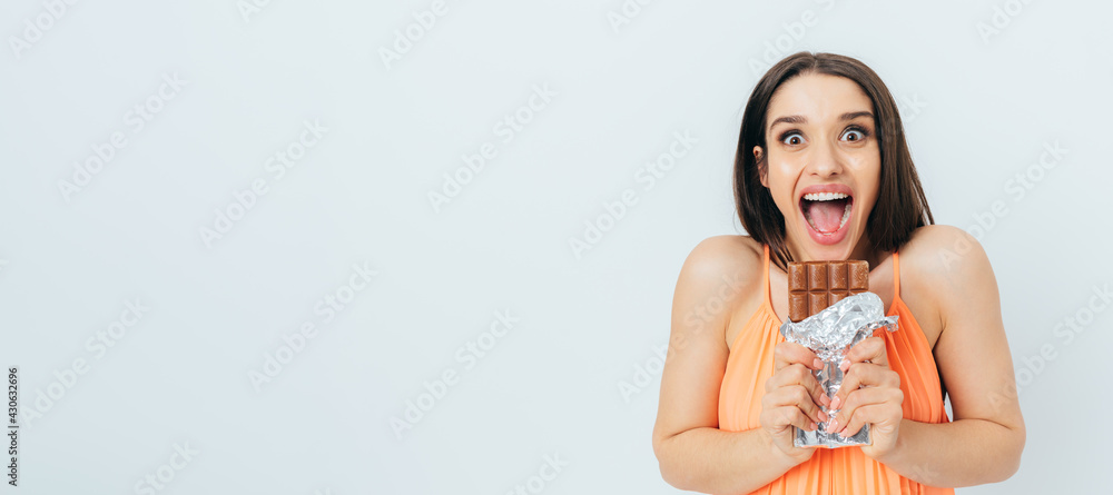 Cheerful excited young woman ready to eat chocolate bar Cheerful excited young woman ready to eat chocolate bar