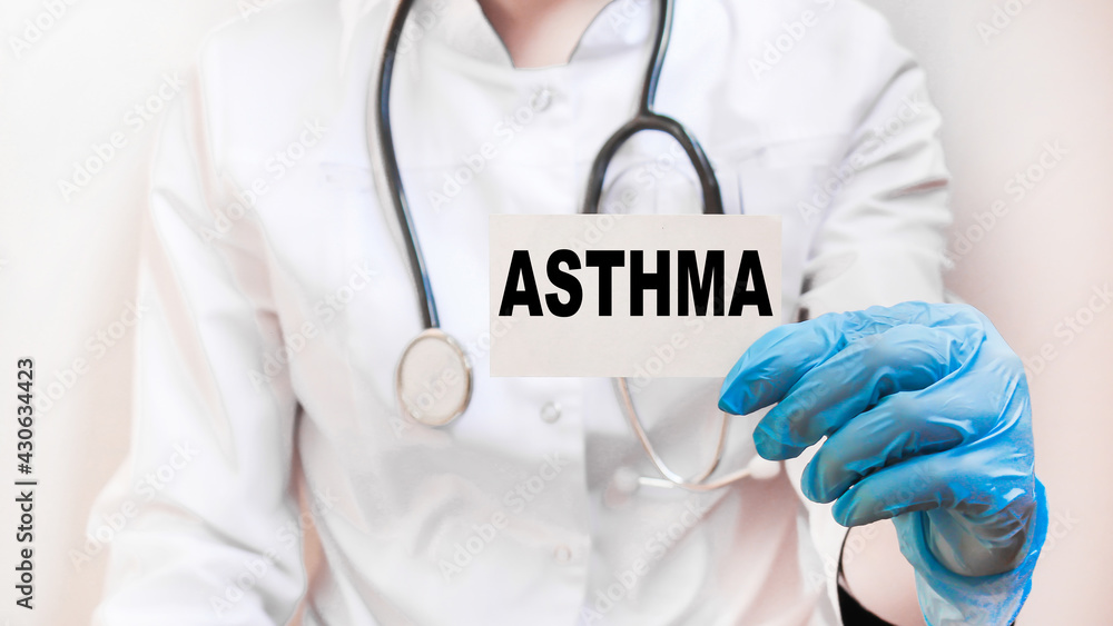 the doctor in gloves holds a card with the text ASTHMA . white background. the medicine the doctor in gloves holds a card with the text ASTHMA . white background. the medicine