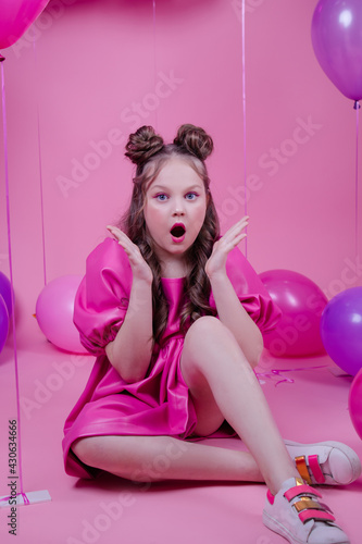 pretty brunette girl teenager with blue eyes and pink make up among balloons on pink background. party, birthday, holiday