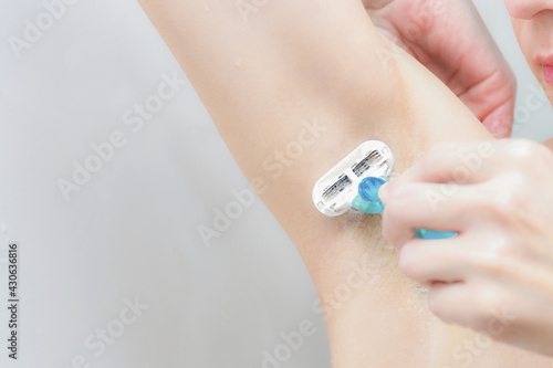 The girl in the shower shaves her armpits with a shaving machine © andov