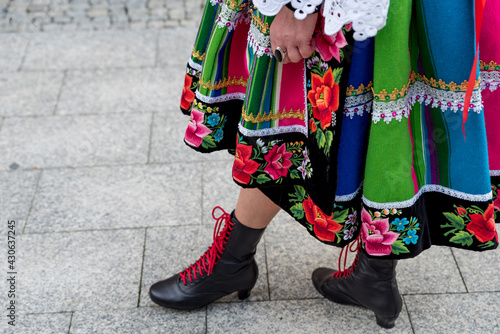 Woman dressed in polish national folk costume from Lowicz region. Close up of traditional colorful striped Lowicz folk dress, shoes and embroidery