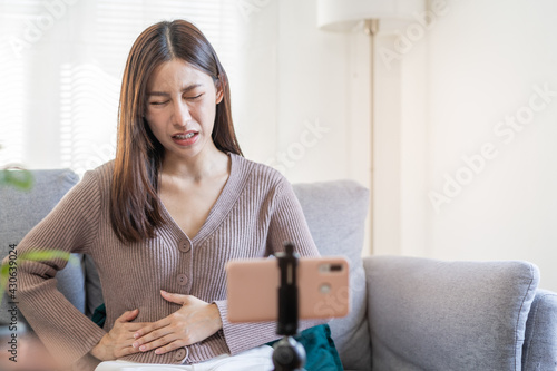 Flatulence asian young woman, girl or Patient hand in stomach ache suffer food poisoning, abdominal pain and colon problem, gastritis or diarrhoea.Telemedicine or telehealth on smartphone concept.
