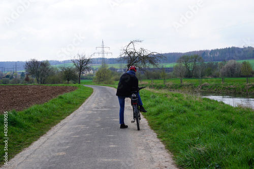 Ein Radfahrer steht auf einem Radweg in den Leinewiesen bei Alfeld Leine