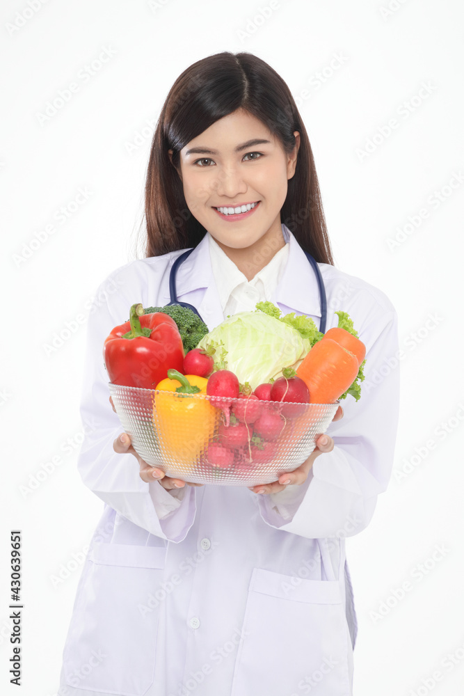 Beautiful young Asian female doctor has a beautiful smile. Holding a bowl of fresh organic vegetables Food for good health. Prescription food nutrition concept, healthy eating. White background. Beautiful young Asian female doctor has a beautiful smile. Holding a bowl of fresh organic vegetables Food for good health. Prescription food nutrition concept, healthy eating. White background.