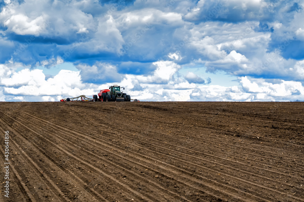 sowing work in the field in spring. Tractor with seeder sowing work in the field in spring. Tractor with seeder