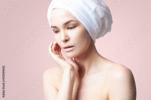Cute positive girl in towel on her hair on pink background