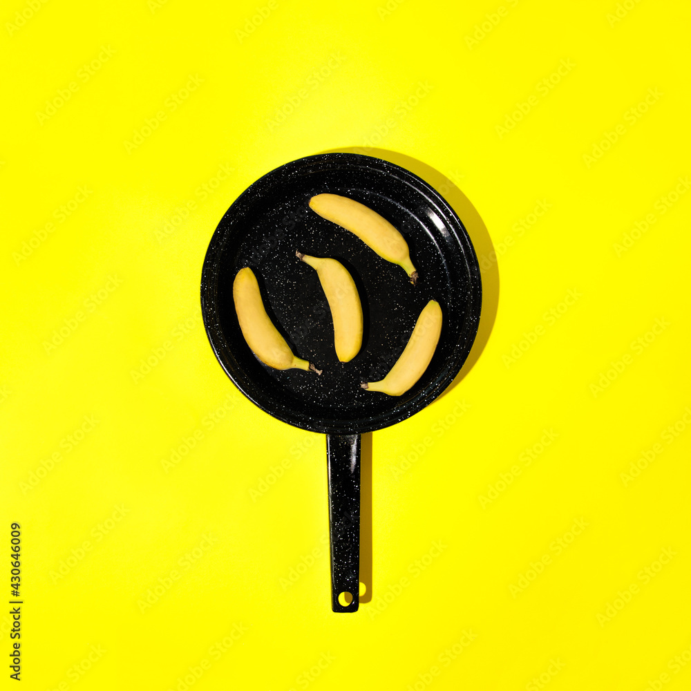 Yellow mini bananas in a pan. On a yellow background. Minimal composition in the kitchen. Yellow mini bananas in a pan. On a yellow background. Minimal composition in the kitchen.