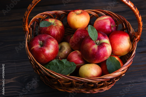 Red sweet apples in a basket on a textured wooden background