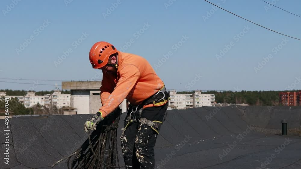 Tired and dirty industrial climber with beard pulling the rope on the roof after work. Sunset. Outside Tired and dirty industrial climber with beard pulling the rope on the roof after work. Sunset. Outside