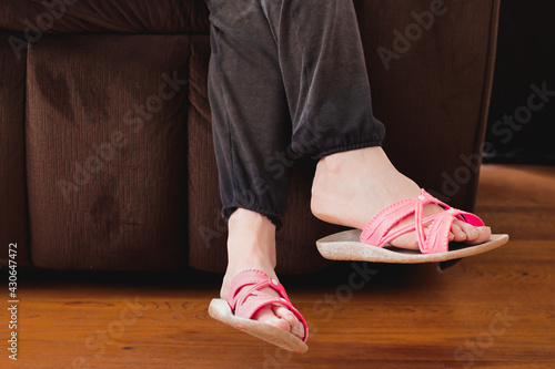 Female bare feet in pink sandals while relaxing on couch or sofa.