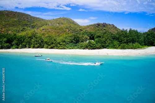 Fototapeta Naklejka Na Ścianę i Meble -  Drone field of view of speeding boat in turquoise water Curieuse Island, Seychelles.