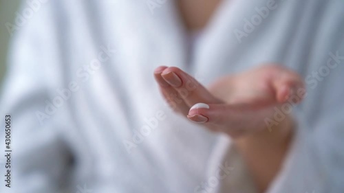 Closeup of female hands are holding bottle with dispenser. Young woman is going to smear apply her eyes with moisturizing, nutrition, anti wrinkle cream after bath. Personal hygiene and care product.