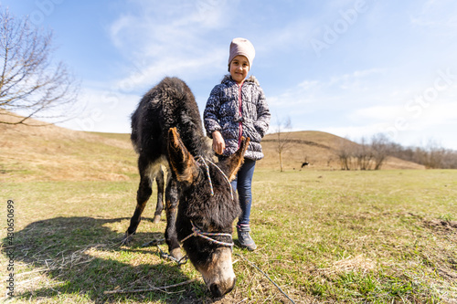 little girl petting a donkey in spring time
