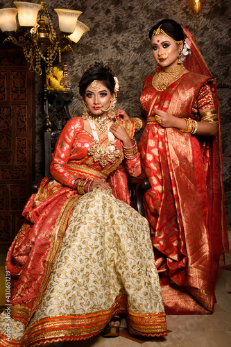 Magnificent young Indian brides in luxurious bridal costume with makeup and heavy jewellery with classic vintage interior in studio lighting. Wedding Lifestyle and Fashion