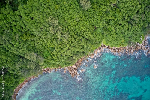 Drone field of view of turquoise blue waters meeting coastline of green forest Praslin, Seychelles. © Tristan Barrington