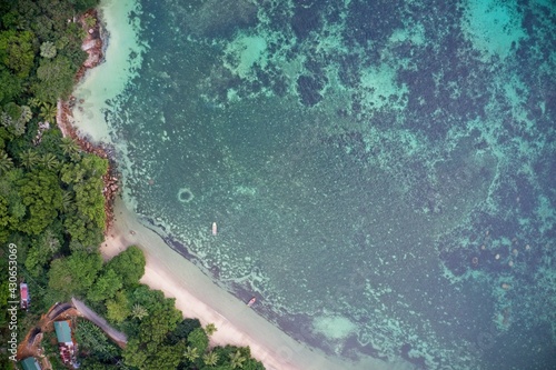 Drone field of view of fishing boats and pristine coastline and forest Praslin, Seychelles.