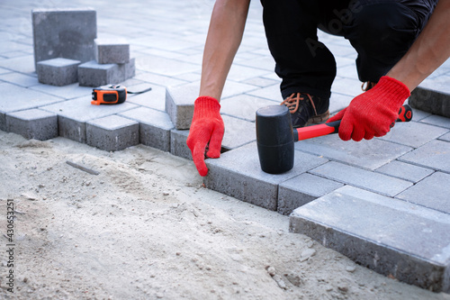 The master in yellow gloves lays paving stones photo