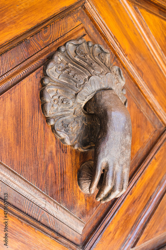 Closeup of a creative hand-shaped doorknob on a wooden door photo