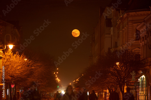 Street of the night city against the background of the rising moon