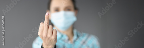 Fotografie Woman in protective medical mask showing middle finger of hand closeup